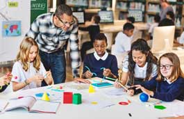 A teacher and students in the classroom sat around a large table, with materials in front of them