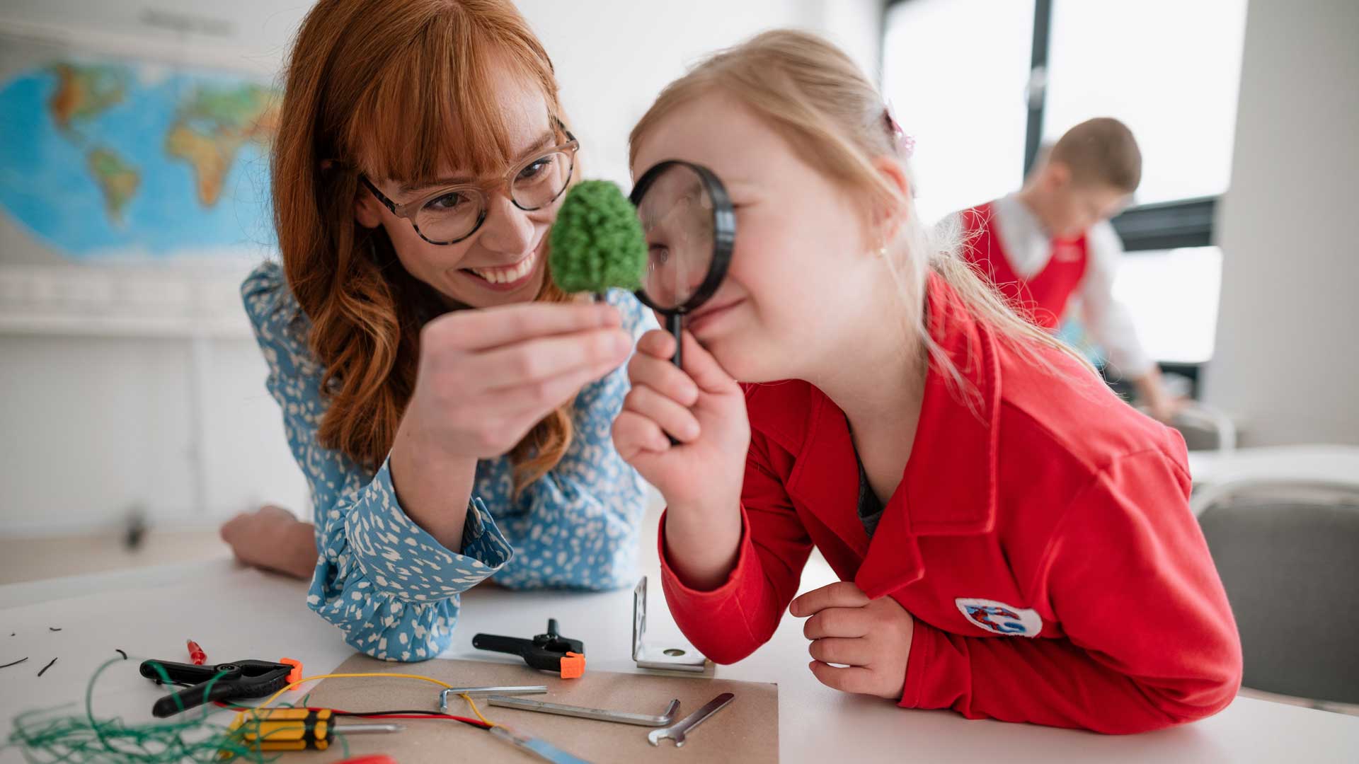 A primary school student with Down syndrome with a teacher, programming electric toys and robots in a classroom.