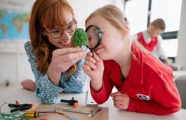 A primary school student with Down syndrome with a teacher, programming electric toys and robots in a classroom.