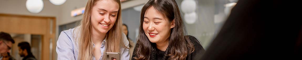 2 female students one white and one chinese laughing together