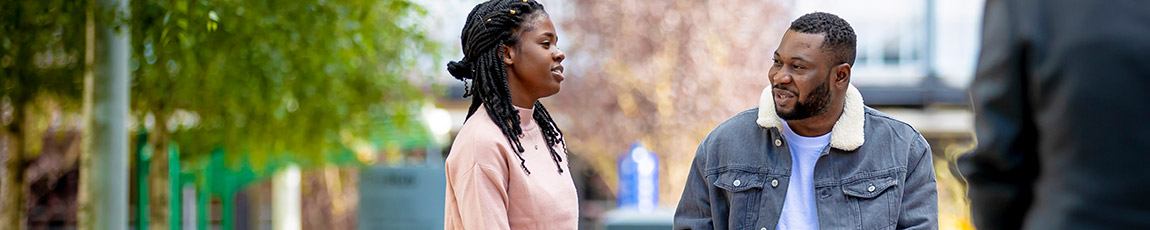 Two students stood outside looking at each other