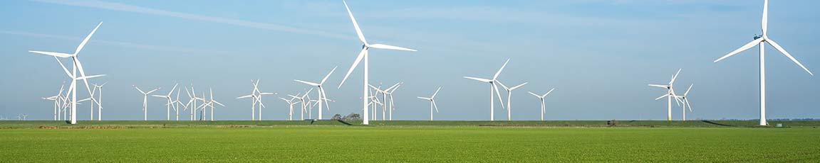 windfarm in the distance in green field with blue sky