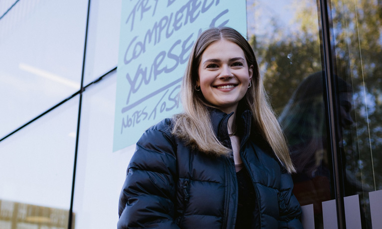 Smiling female student standing outside the Student Hub