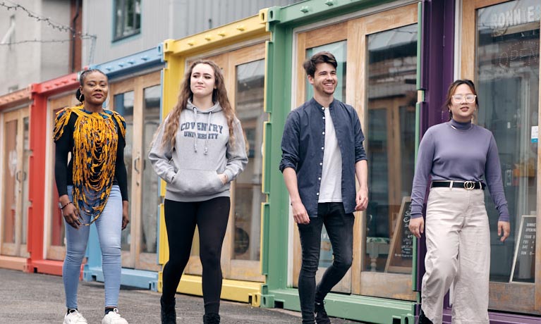 Four students walking through Fargo Village, Coventry's creative quarter.