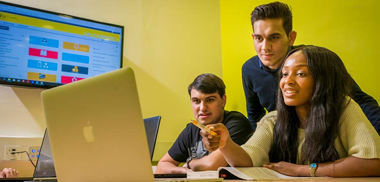 Lecturer and students looking at laptop