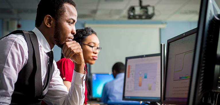 female and male students looking at laptops at desks 