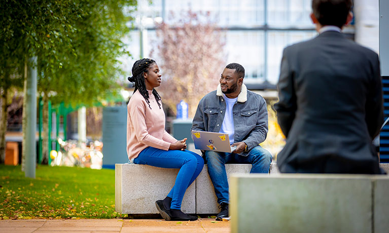 Two students sat outside the hub talking