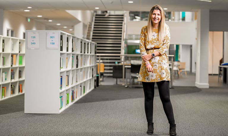 Young female student alongside books in a library