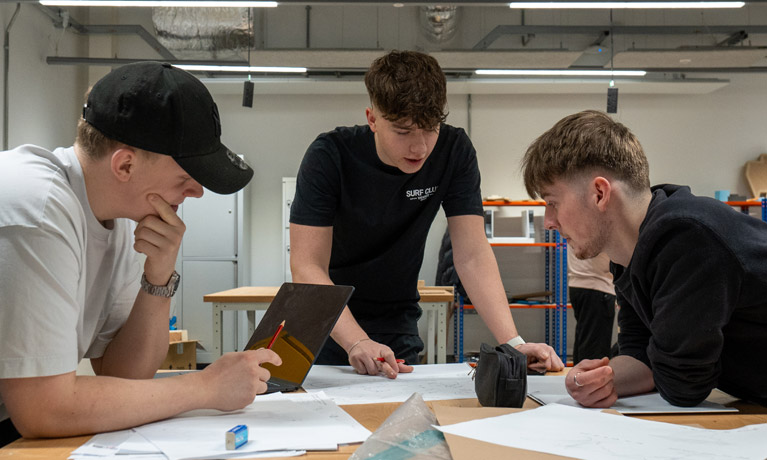 Three students at a table working together on a product design project