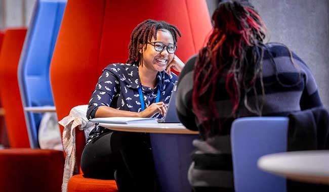 2 students smiling and chatting together in a booth 