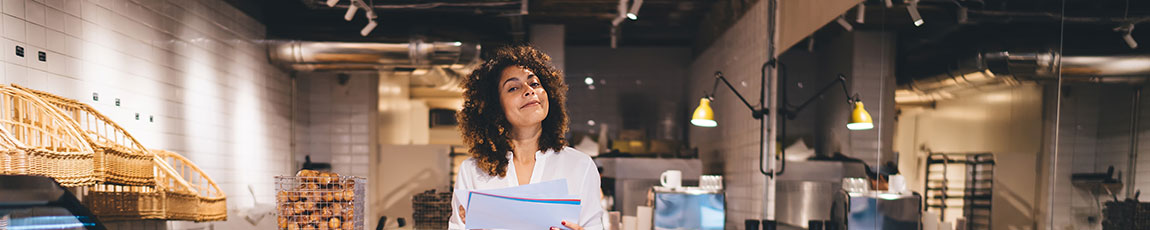 Smiling woman in a cafe holding paper