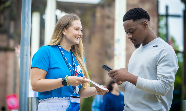 A student taking phone details with a Students' Union rep helping him.