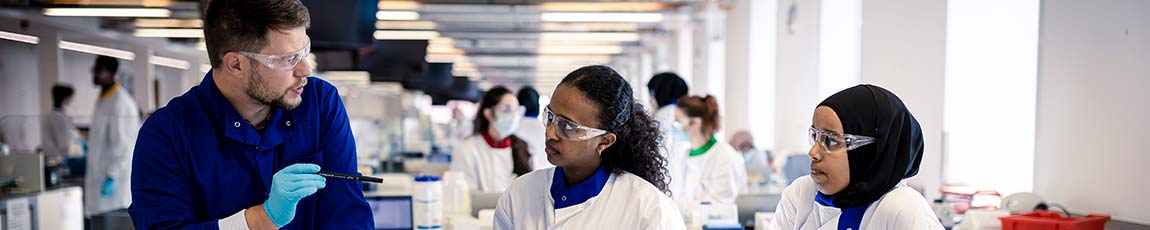 Lecturer teaching two students in a lab