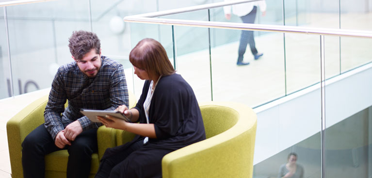 Two people sitting down talking looking at a screen