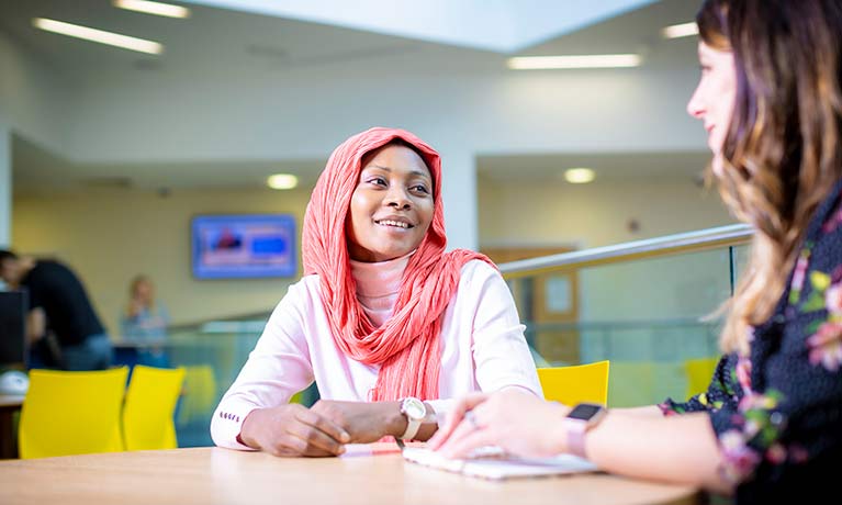 A student smiling and talking with a staff member.