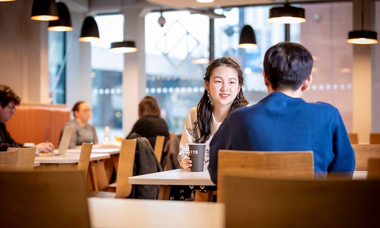 Two students sat at a desk talking to each other