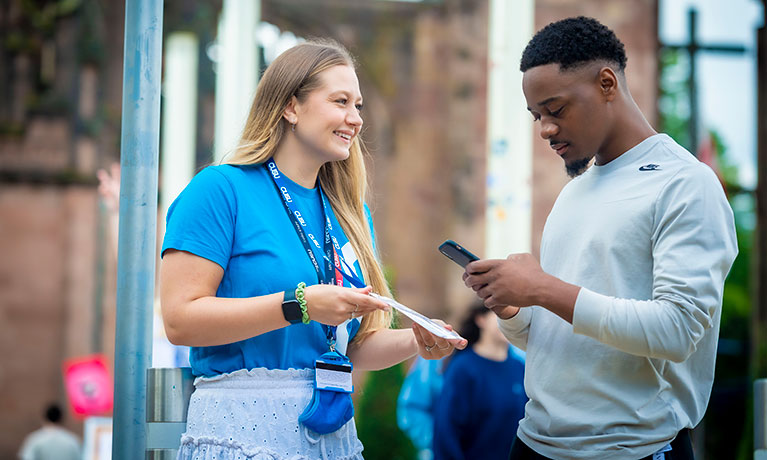  Student talking with a member of staff in university square