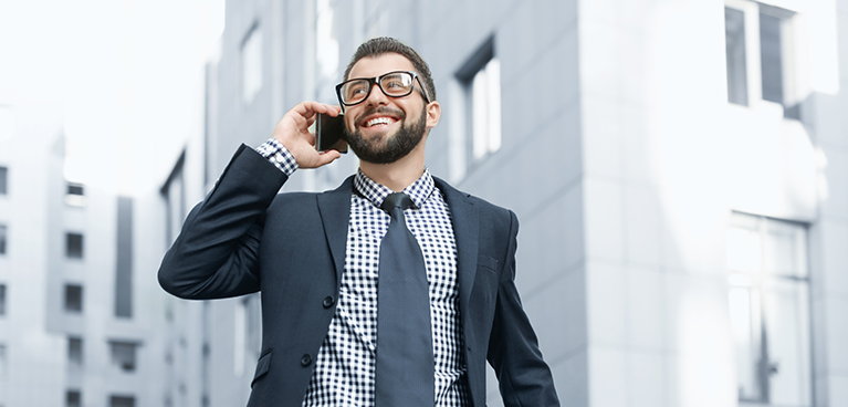 Business man in suit on phone outside building.