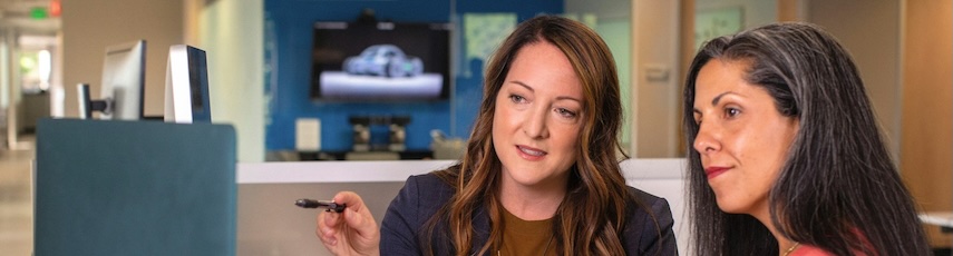 two women looking at a computer screen and discussing content