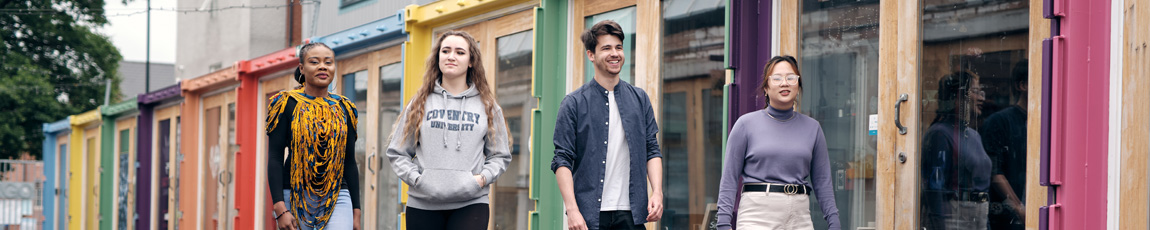 Four students walking past colourful shop fronts in Fargo Village.