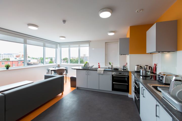 Open kitchen with cupboards and oven with a large sofa