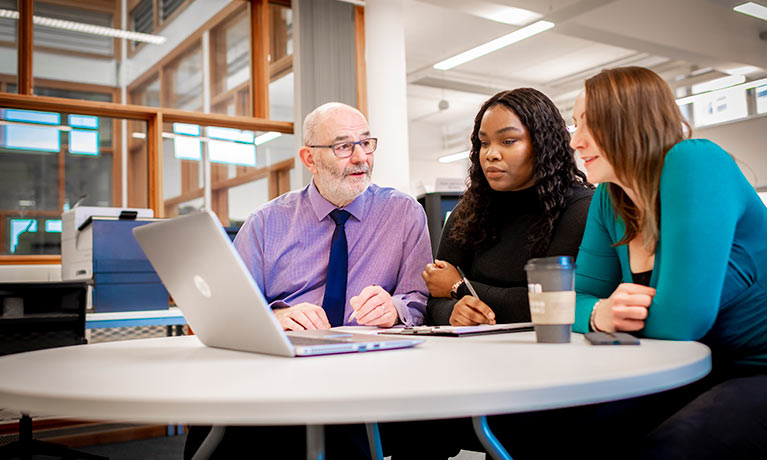 A tutor and two students looking at a laptop in the sigma Centre