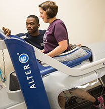 Woman on assessment machine while man leans over to adjust settings