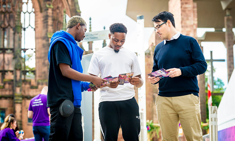 Three students stood outside the cathedral looking at a phone