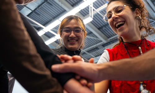 A group of students doing a team hand stack and smiling