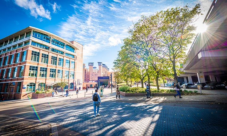 Old building on a sunny day surrounded by people and leafy trees