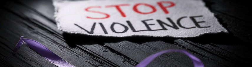 Image of a scrap of paper that says "Stop Violence" on it with a purple ribbon bow in front of it