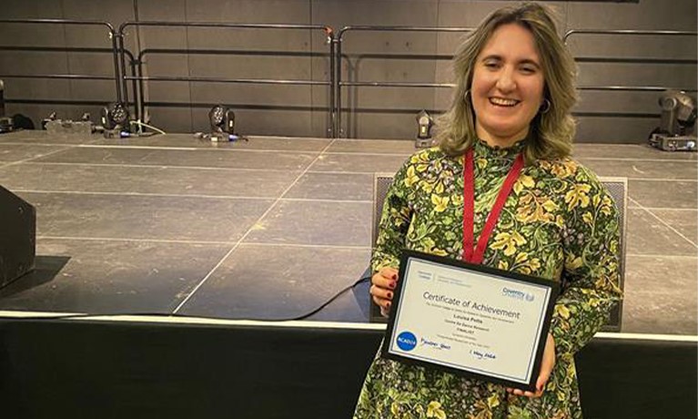 Postgraduate researcher Louisa Petts standing with her certificate