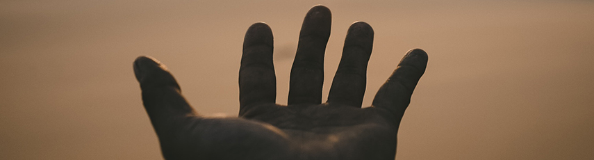 Outstretched hand against beach sand background