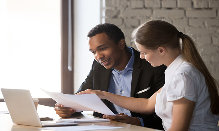 A male and a female wearing business attire reviewing a document