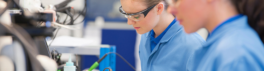 Women technicians soldering circuit boards on production line in a manufacturing plant