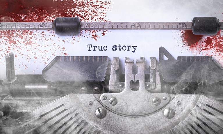 A typewriter and a piece of paper splattered in blood that reads "true story".