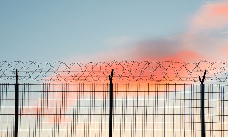 Wire mesh fence with colourful sky background
