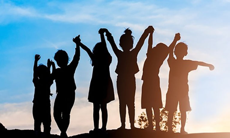 Silhouette of children with arms raised against a blue sky