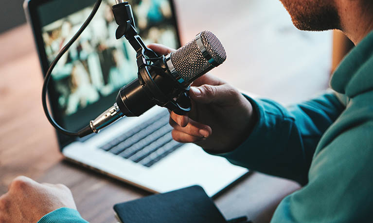 Someone working at a laptop, with a separate microphone