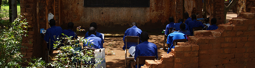 People working at chairs in a bombed out school in Sudan