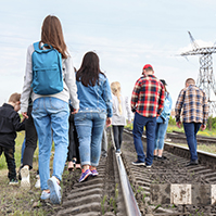 Group of asylum seekers walking on train tracks