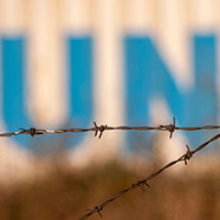 UN logo on a wall behind barbed wire