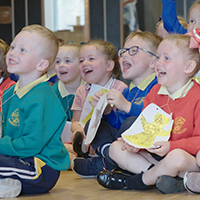 A group of smiling primary school children sitting on the floor