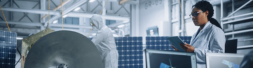 Female Engineer Uses Tablet Computer while Working on Satellite Construction