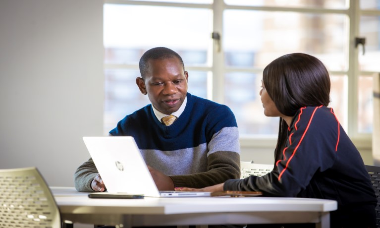 two people collaborating with a laptop on the desk