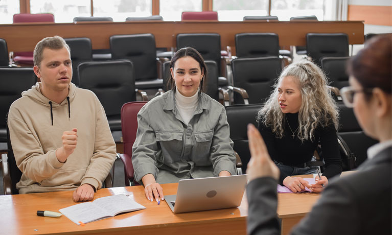 Three deaf students chatting in a university classroom.