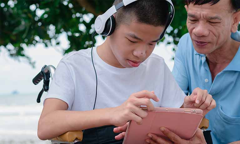 Boy in wheelchair using a tablet.