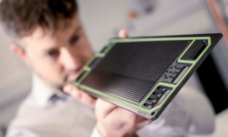 close of of a black and green circuit board with an out of focus person inspecting it lab