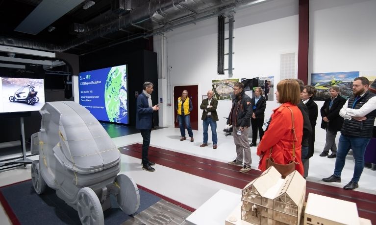 Group of 15 people listen to a professor inside the NTDC building during the transport expo