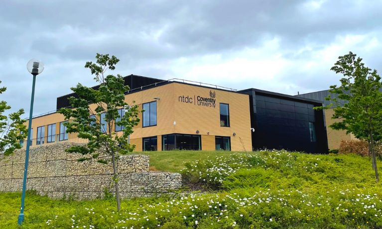 image of the NTDC building on top of a grassy verge with grey clouds in the background 